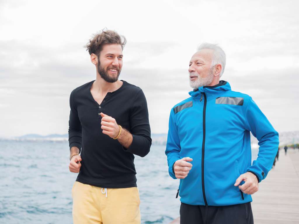 Junger und älterer Mann laufen am Strand