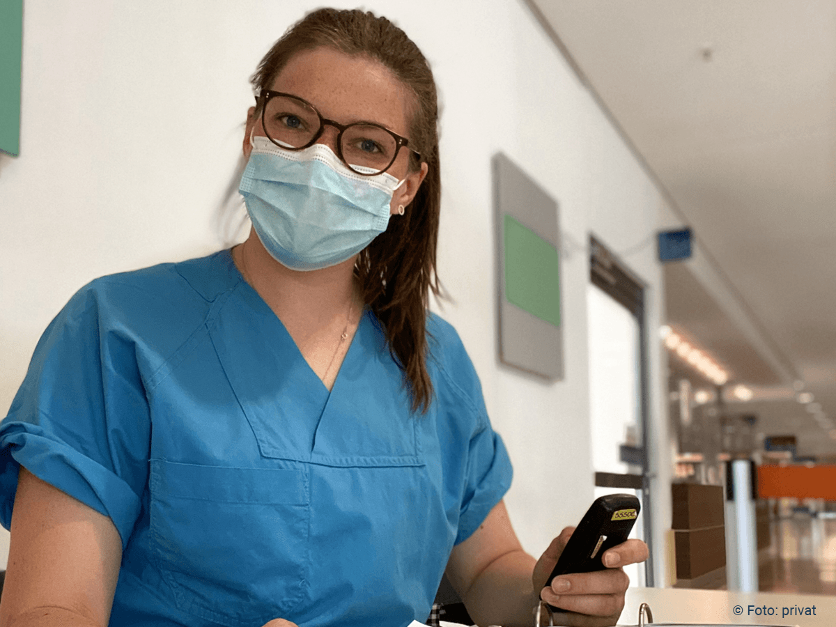 Foto: Studierende mit Mundnasenschutz sitzt im Krankenhaus am Covid19-Checkpoint