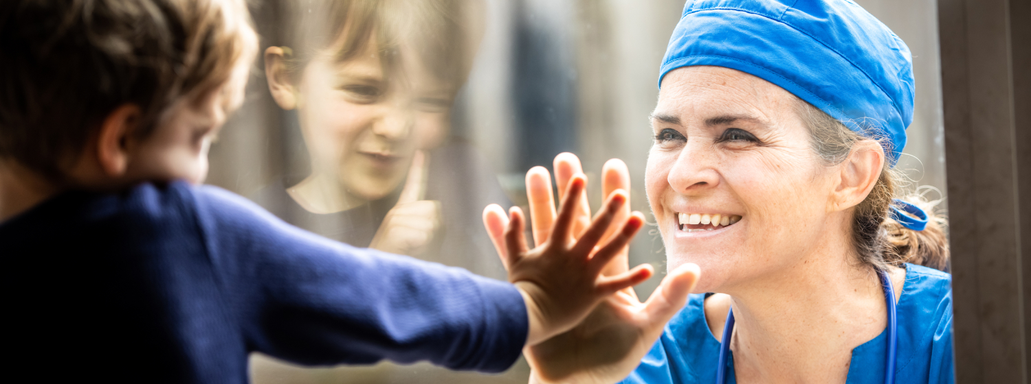 Ärztin mit Kind Bild: Ärztin und Kind berühren die Hände durch eine Scheibe