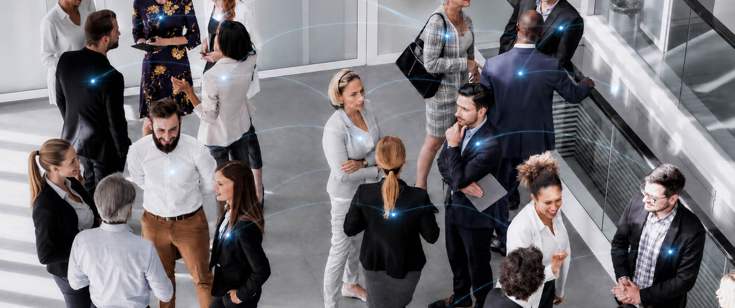 Gruppe von Menschen in Geschäftskleidung steht in einem modernen Büro und unterhält sich in kleinen Gruppen