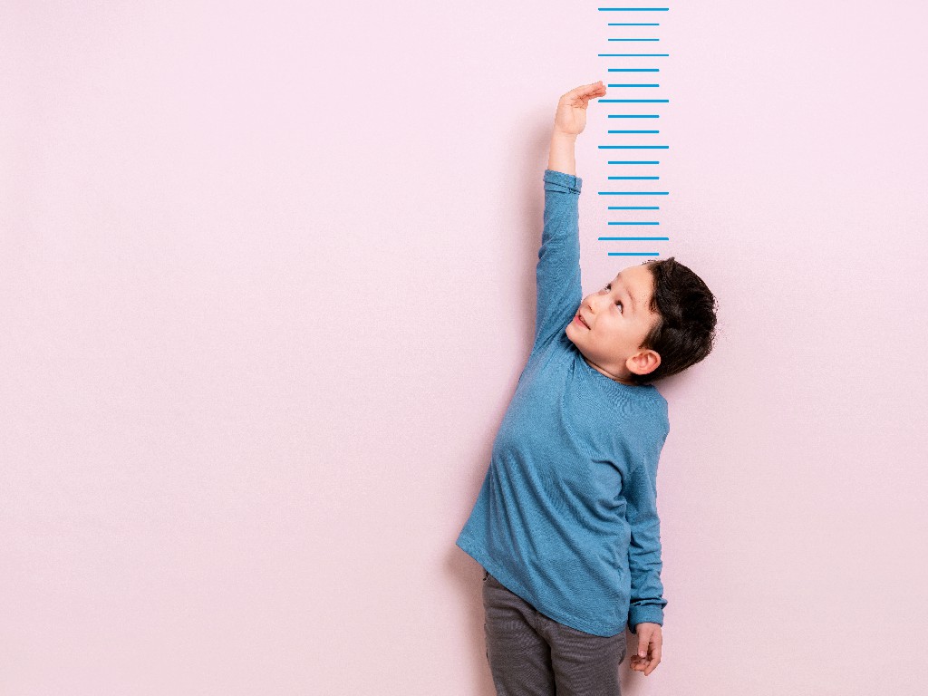 Kleiner Junge prüft seine Größe an der Wand