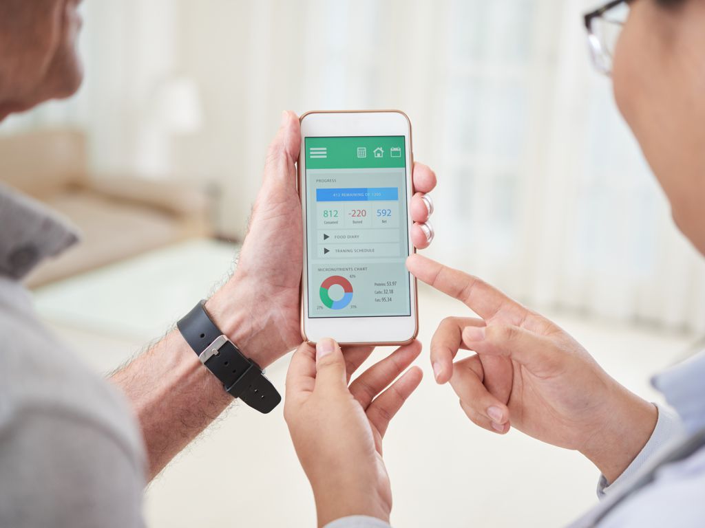 Aerztin schaut mit dem Patient auf eine Digitale Gesundheitsanwendung auf dem Smartphone