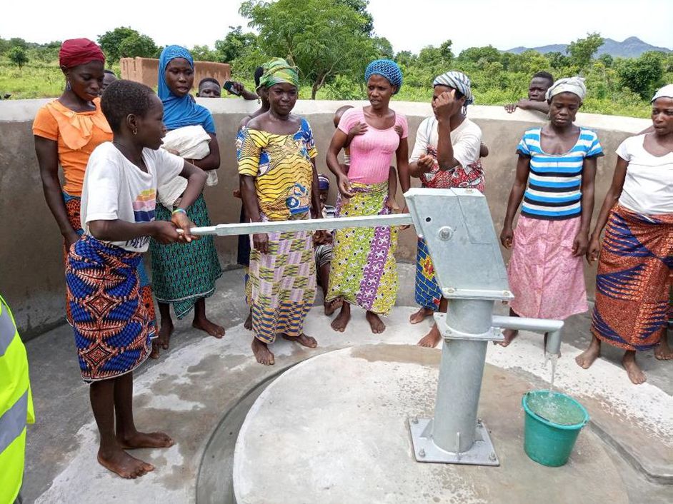 Frauen in Kissabombik stehen um einen Brunnen 