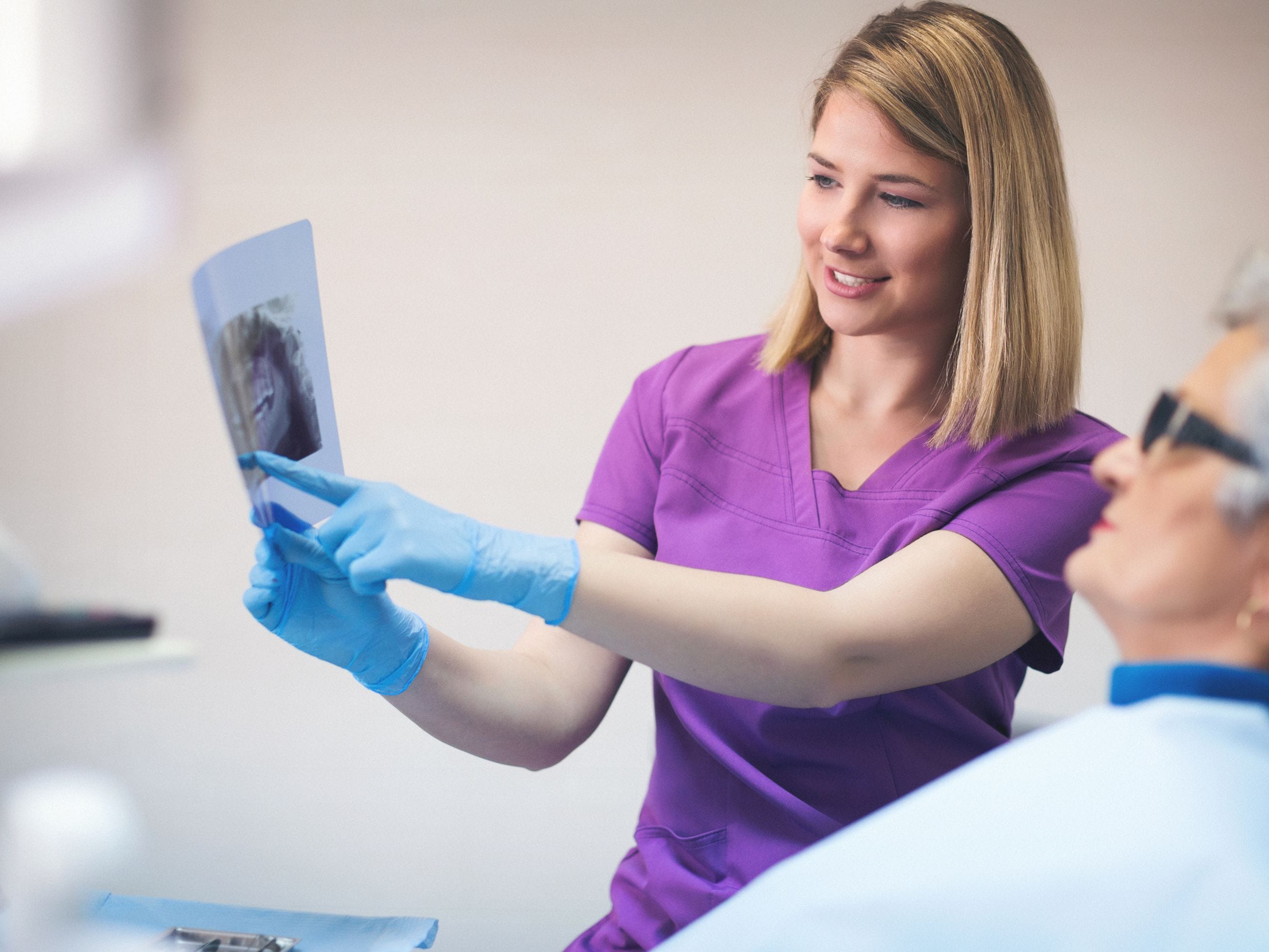 Zahnärztin mit Röntgenbild bei Patientin