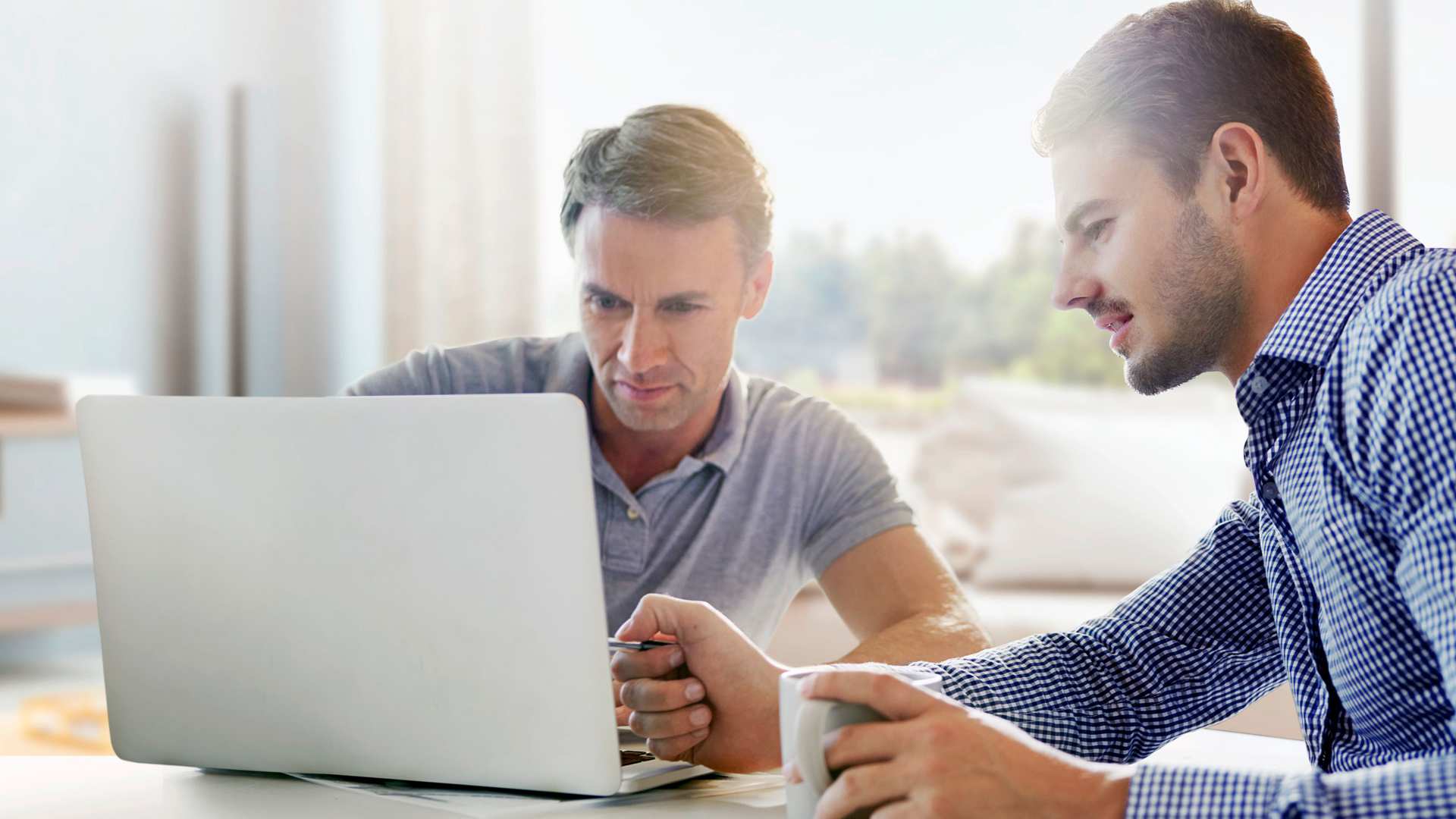 apoBank Depotanalyse Zwei Männer am Schreibtisch, blicken in ein Notebook
