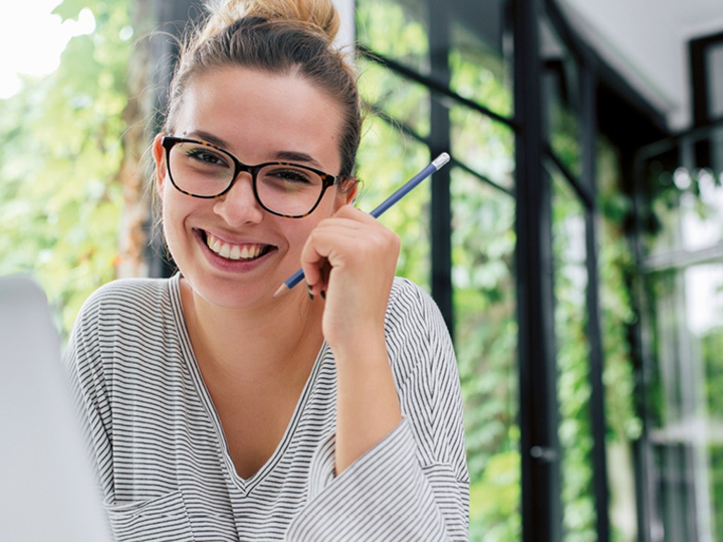 Junge Frau am Schreibtisch mit Bleistift in der Hand