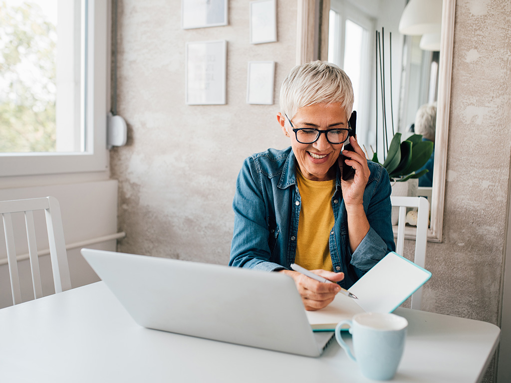 Telefonbanking-Frau mit Smartphone und Notebook